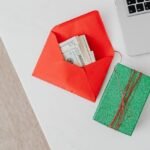 An envelope with cash and a gift box next to a laptop, symbolizing the ease of receiving a Direct Deposit Bonus