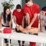 Paramedic education students practicing CPR on a mannequin during a hands-on training session, learning vital life-saving skills in a classroom setting.