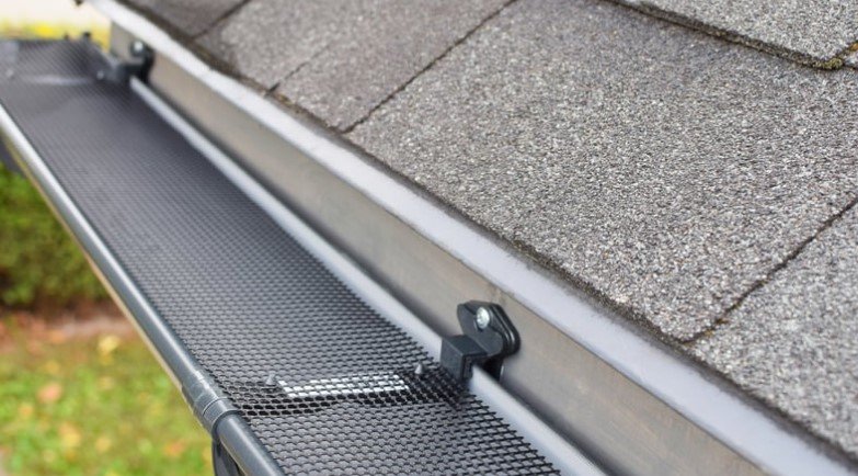 A close-up view of a gutter guard installed on a roof, protecting gutters from debris and ensuring proper water flow, helping to prevent damage to the home.