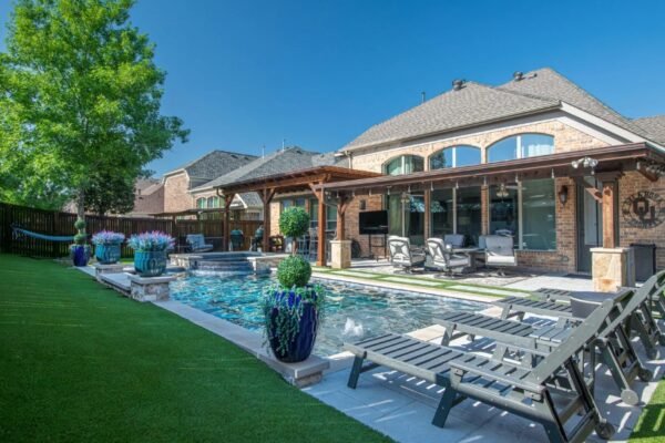 A beautiful backyard featuring a pool, seating area, and lush greenery, showcasing the ultimate in outdoor living space design.