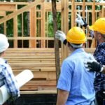 Construction workers discussing plans during a pre-construction survey on a building site, reviewing site conditions before starting construction.