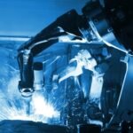 A robotic welding arm in action, creating sparks while performing automated welding in a factory setting.