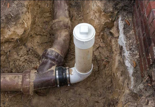A sewer line clean out pipe installed in the ground, showing the capped access point for plumbing maintenance and repairs.