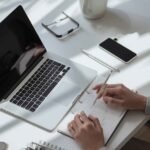 Workspace featuring a laptop, notebook, and phone, representing a productive environment in testissä