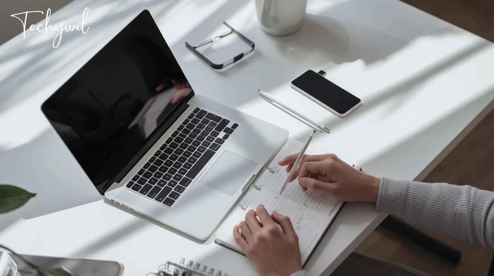 Workspace featuring a laptop, notebook, and phone, representing a productive environment in testissä