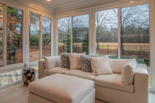 A bright and serene sunroom with vinyl windows showcasing a clear view of the outdoors, offering a quiet and peaceful environment.