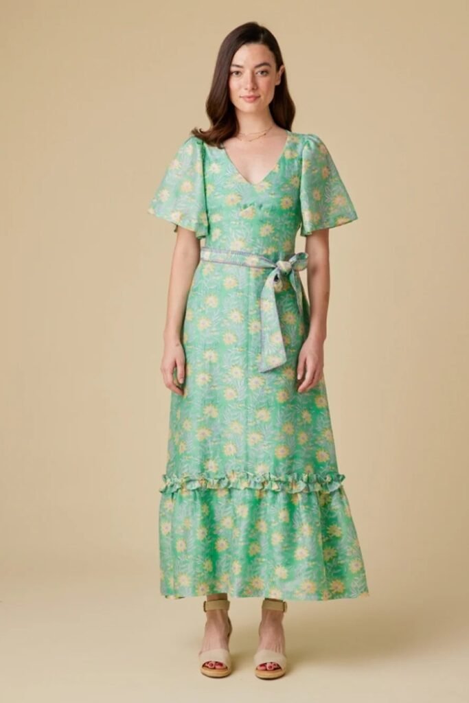 Model wearing a green block print dress with floral patterns and a tied waist, showcasing a refreshing, feminine look with a relaxed style