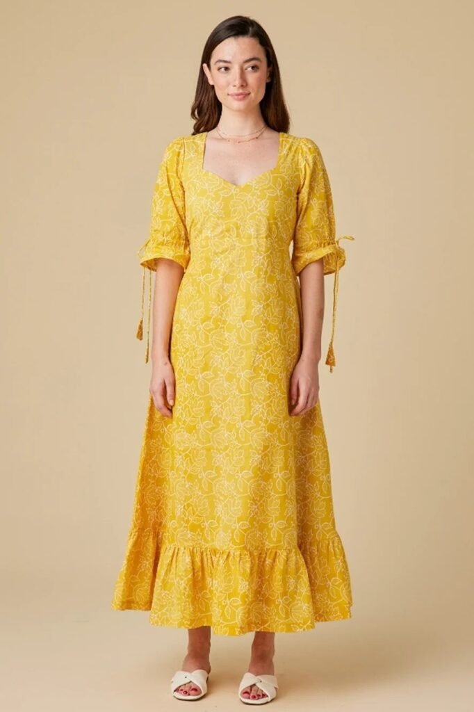 Model wearing a yellow block print dress with floral designs, showcasing the relaxed elegance and timeless beauty of handcrafted fashion