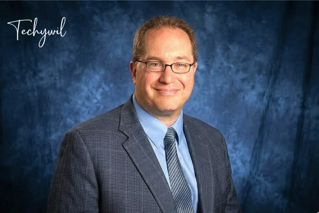 Professional portrait of anthony langone martinsburg wv in suit and glasses against a blue studio background.