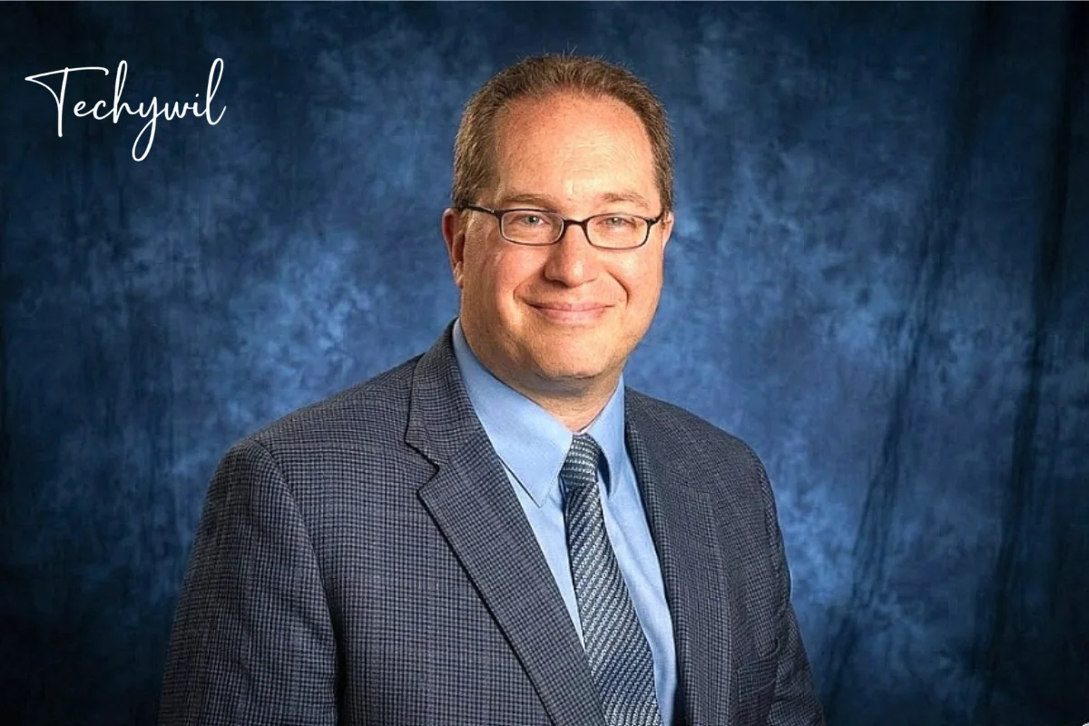 Professional portrait of anthony langone martinsburg wv in suit and glasses against a blue studio background.